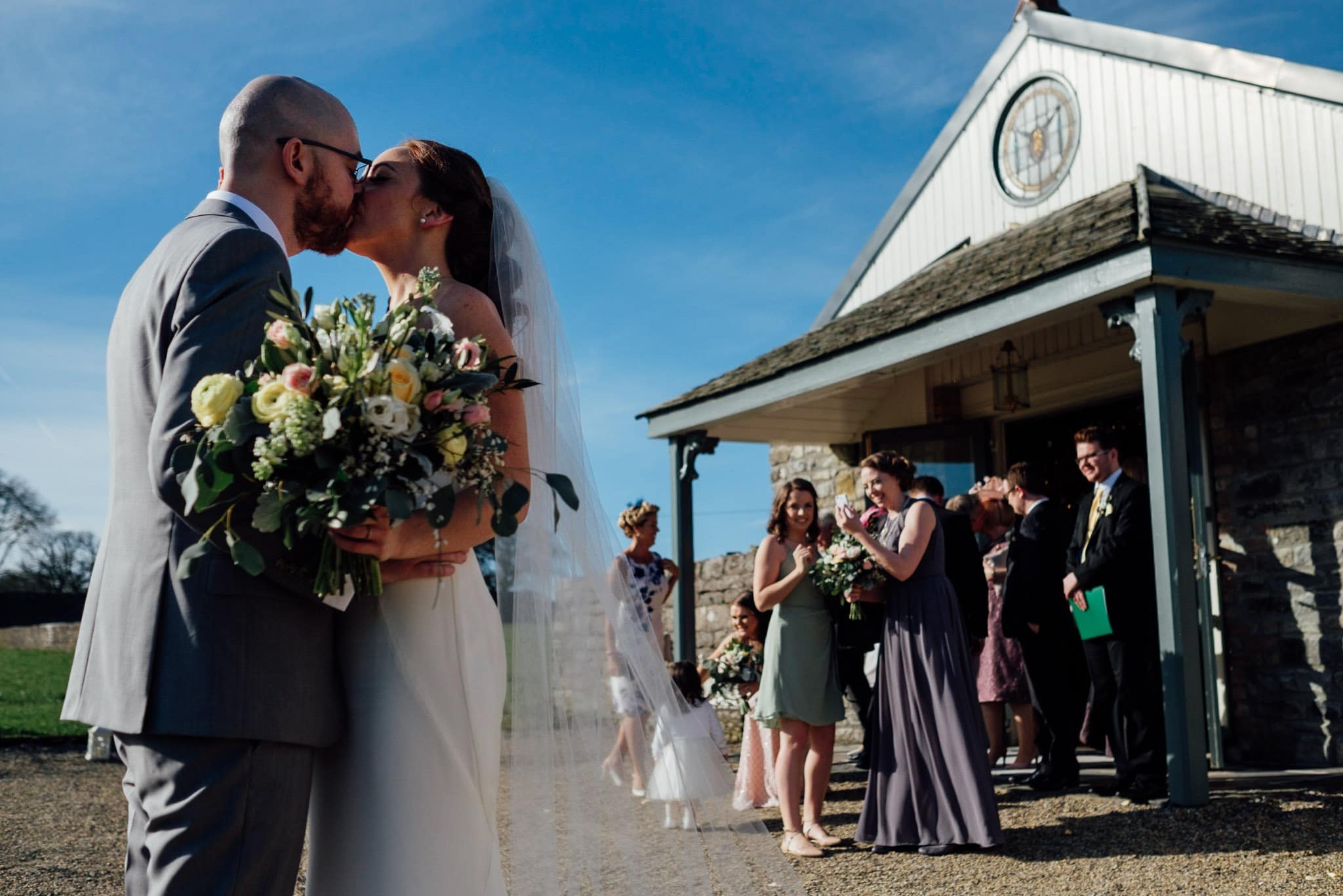 bride and groom kiss outside the ceremony room